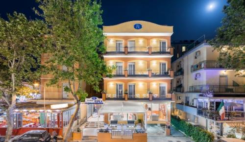 Hotel illuminato di notte, con terrazze e luna sullo sfondo.